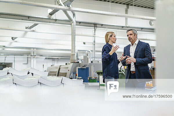 Businessman and businesswoman discussing ideas in factory