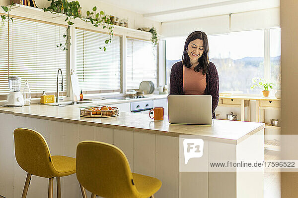 Businesswoman using laptop in kitchen working at home