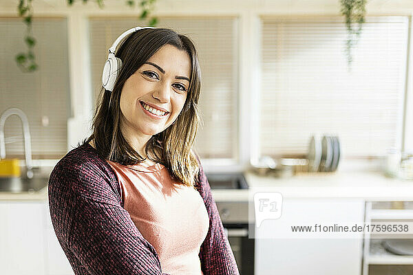 Beautiful woman with headphones smiling in kitchen