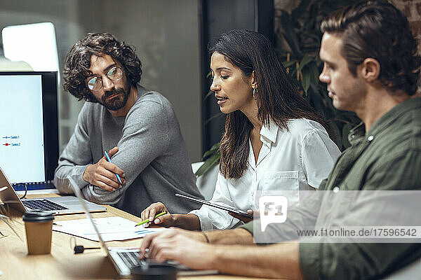 Businesswoman explaining business strategy to colleagues on document in meeting at office