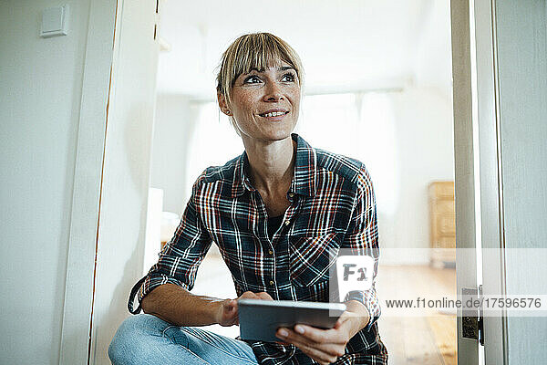 Nachdenkliche Frau mit digitalem Tablet zu Hause