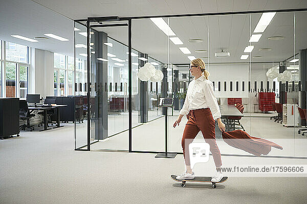 Businesswoman riding on skateboard in office