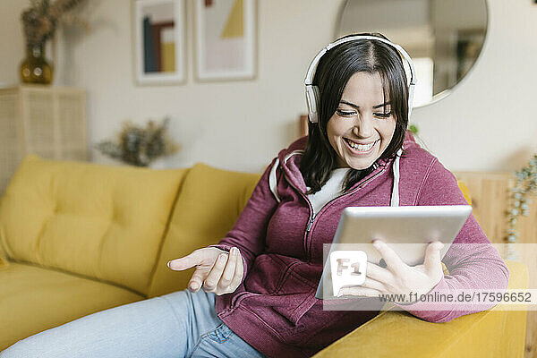 Happy woman gesturing on video call through tablet PC in living room