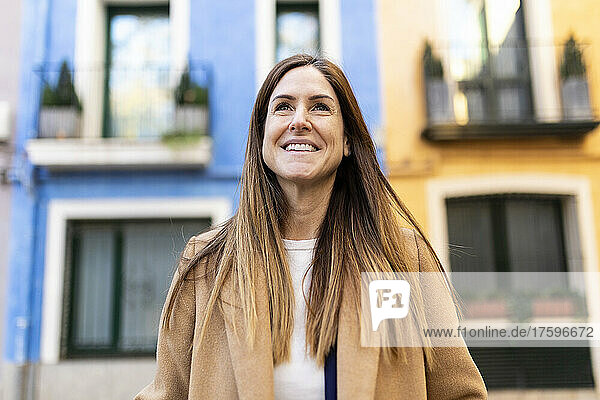 Smiling woman with long brown hair in city