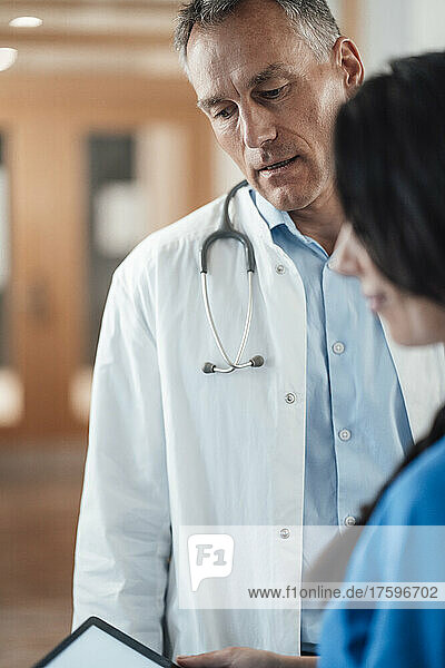Krankenschwester diskutiert mit Arzt über Tablet-PC im Krankenhaus
