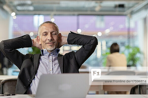 Businessman with hands behind head relaxing in office