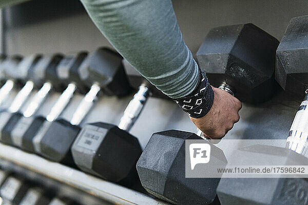 Hands of athlete holding dumbbell in gym