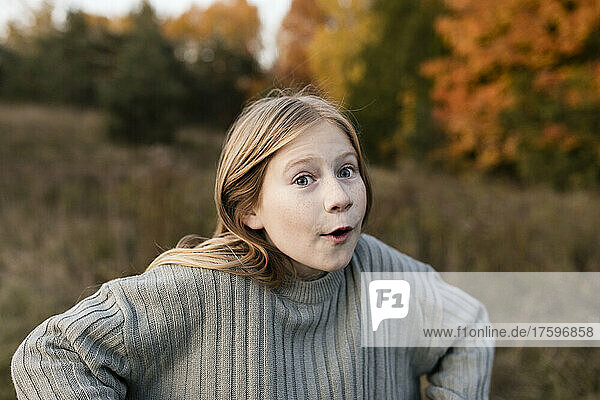 Blond girl making face at autumn park