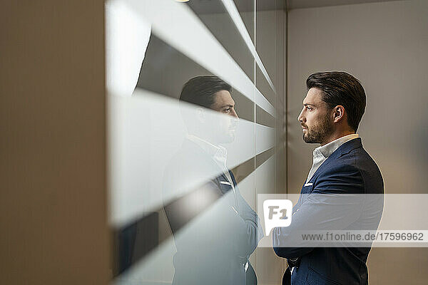 Confident businessman looking through window in office