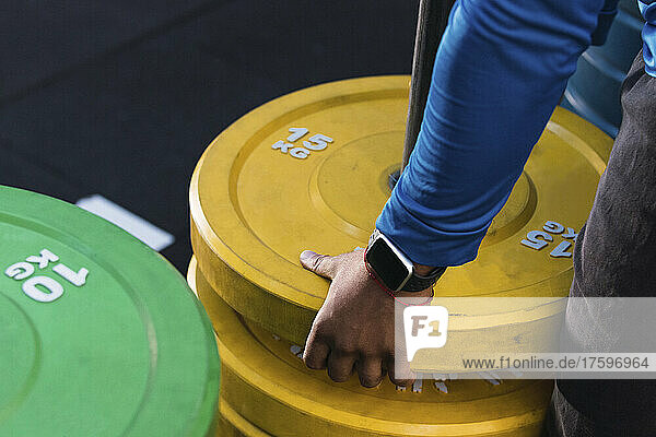 Hands of athlete removing weight plates in gym