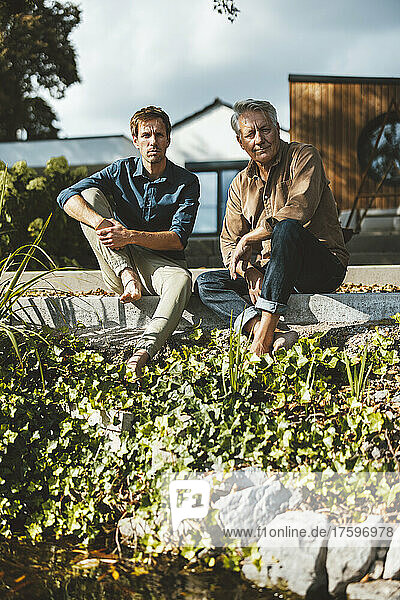 Father and son sitting on steps at backyard