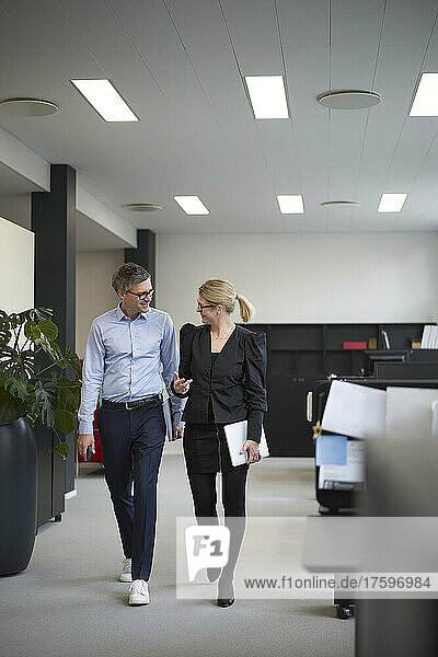 Businesswoman discussing with colleague and walking in office