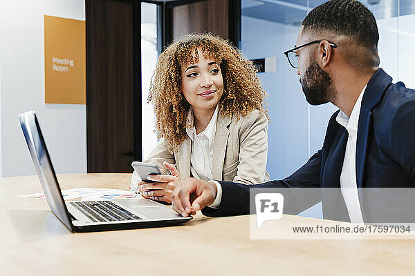 Geschäftskollegen mit Laptop diskutieren im Coworking-Büro miteinander
