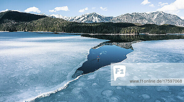 Deutschland  Bayern  Luftaufnahme eines einsamen Mannes beim Paddeln zwischen Eisschollen im Eibsee