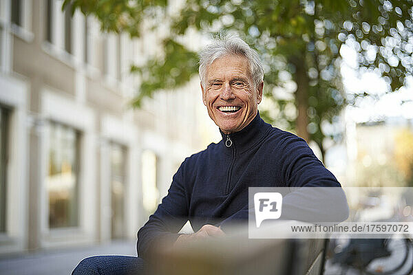 Cheerful senior man sitting on bench
