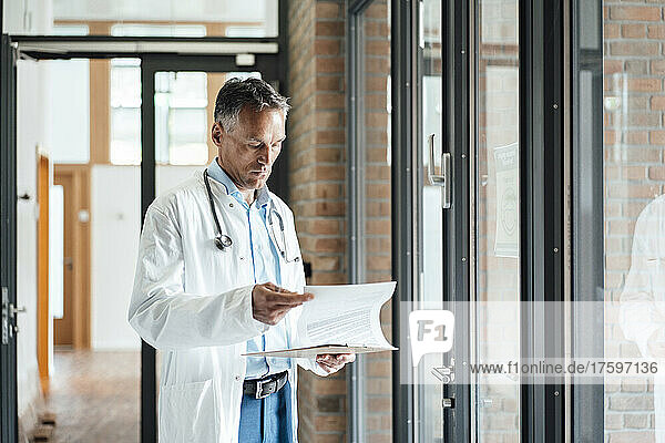 Mature doctor examining medical record in hospital