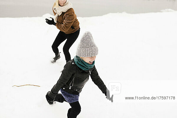 Happy mother and daughter playing with snow in winter