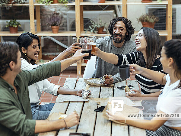 Cheerful businessmen and businesswomen toasting drinks at cafeteria