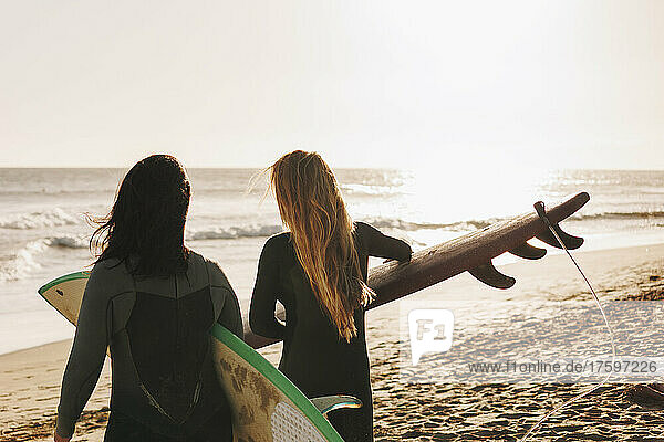 Women with surfboards walking towards shore at beach  Gran Canaria  Canary Islands