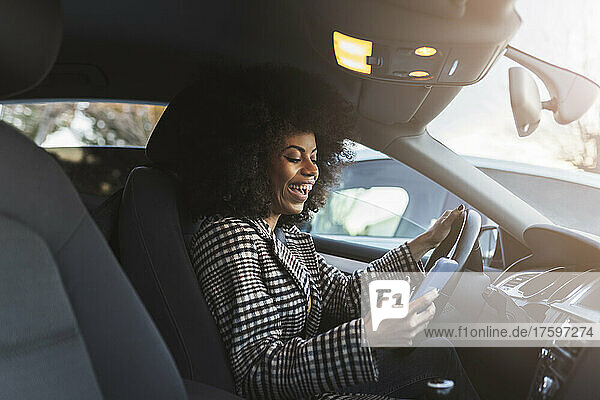 Cheerful woman using smart phone in car