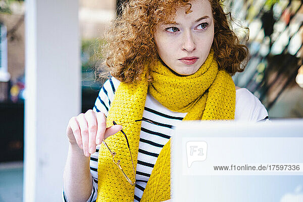 Junge Frau mit Laptop im Straßencafé