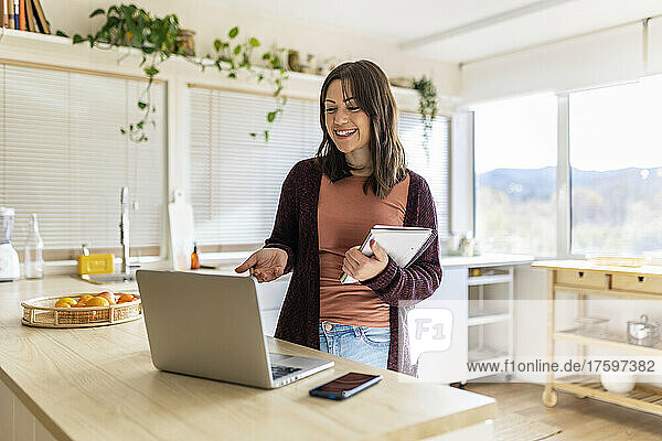 Freelancer with notebook doing video call on laptop at home