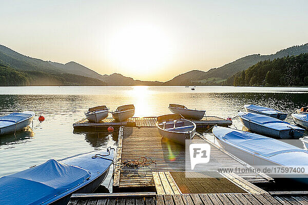 Boats moored along jetty on shore of Lake Fuschl at sunset