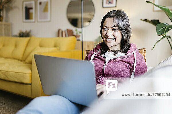 Happy young woman using laptop in living room
