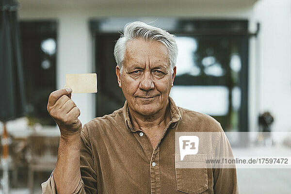 Älterer Mann mit weißem Haar hält Kreditkarte in der Hand