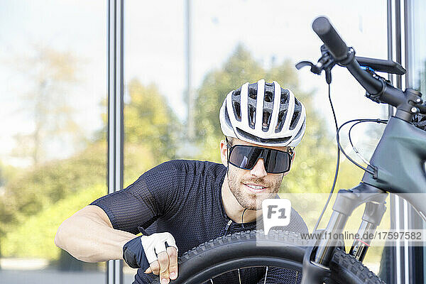 Young cyclist wearing sunglasses and helmet checking tire
