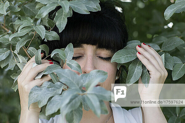 Woman with eyes closed amidst leaves