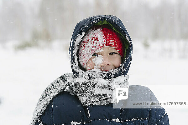 Happy boy with snow on scarf in forest