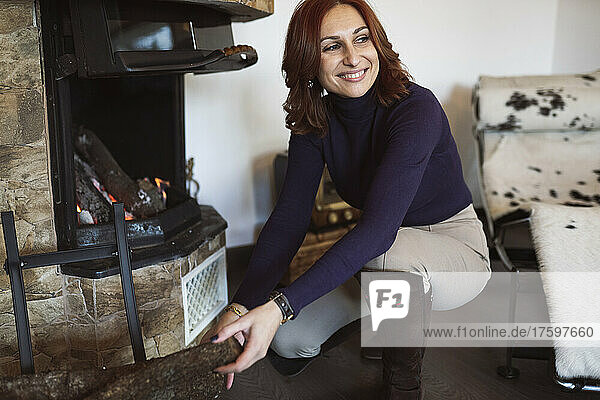 Smiling woman kneeling by fireplace in living room