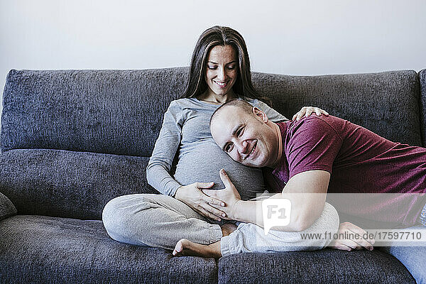 Man listening to pregnant woman's belly at home