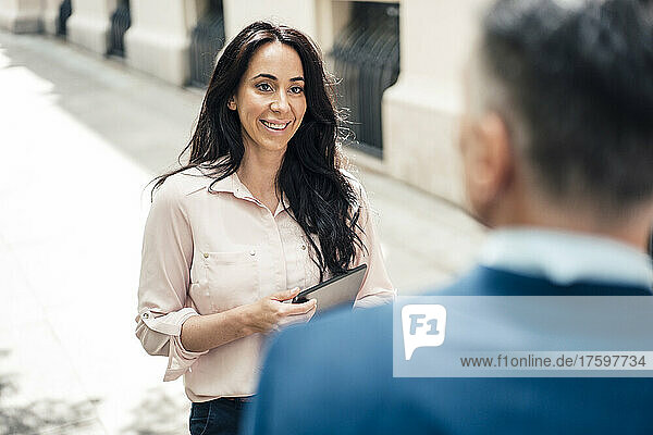 Happy businesswoman talking with businessman on footpath