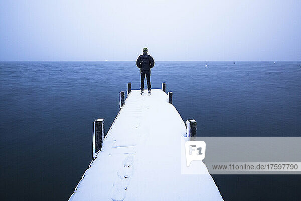 Tourist admiring lake standing on jetty in winter  Walchensee  Bavaria  Germany