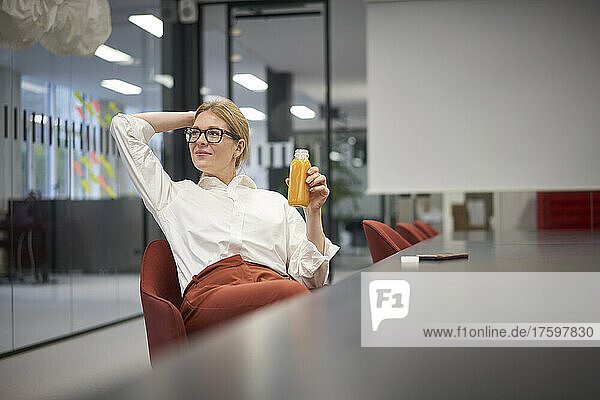Businesswoman with juice bottle sitting in office