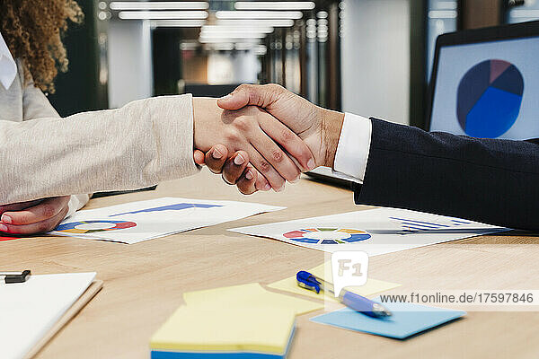 Business colleagues shaking hands at coworking office