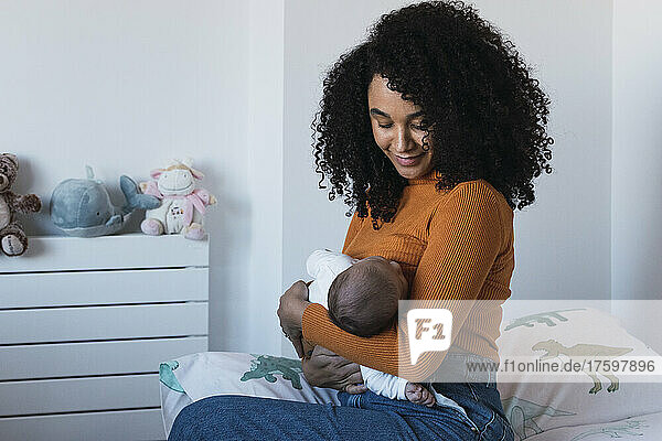Mother breastfeeding baby boy in bedroom