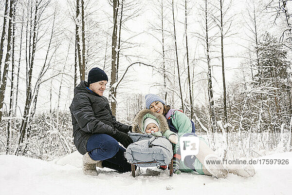 Father and mother with daughter enjoying snow in winter forest