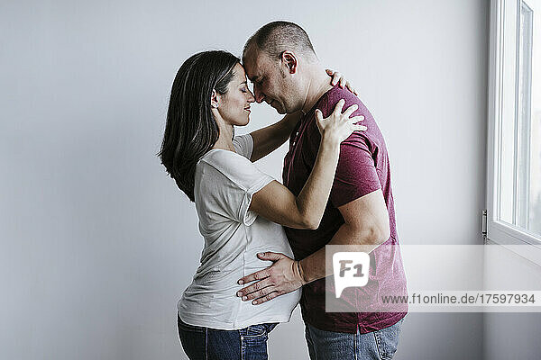 Pregnant woman embracing man at home