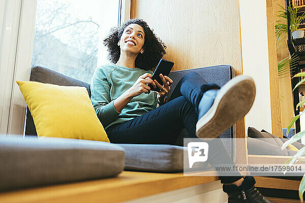 Contemplative businesswoman with smart phone on sofa