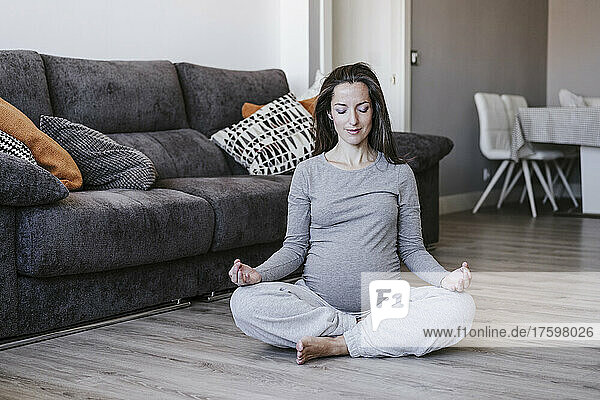 Pregnant woman practicing lotus position at home