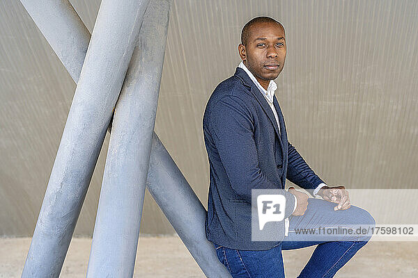 Bald businessman leaning on metallic structure