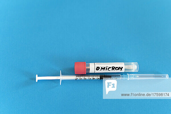 Swab tube and vaccine syringe on blue background