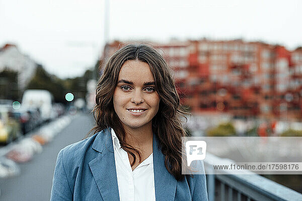 Smiling young businesswoman on bridge