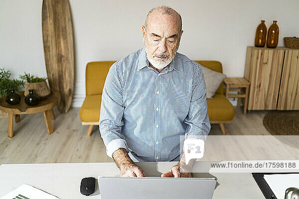 Serious businessman using laptop at desk