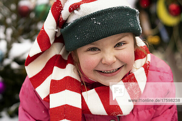 Happy cute girl wearing striped scarf in winter