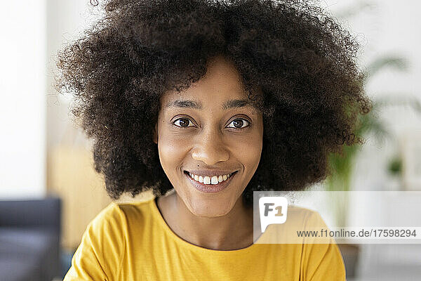 Happy young woman with black curly hair at home