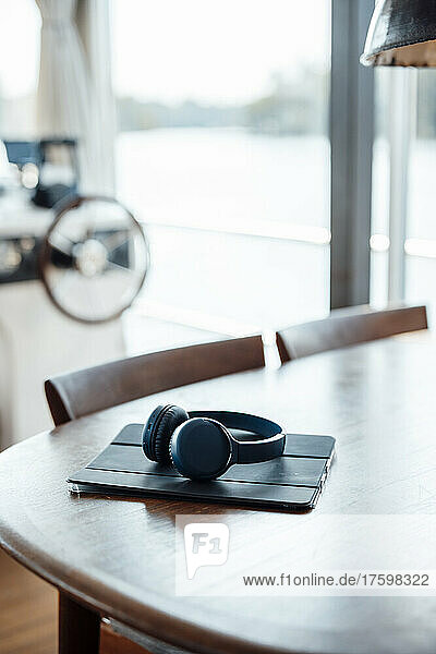 Tablet PC and wireless headphones on wooden table at houseboat